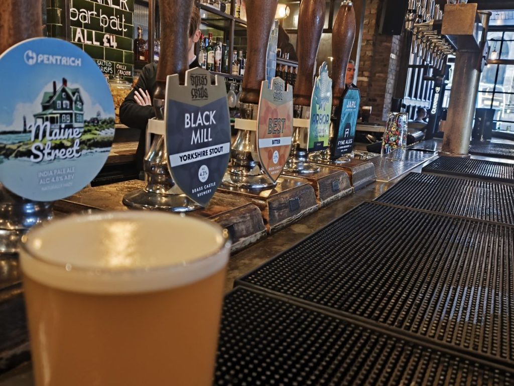 Bar at the Gunner Tavern Newcastle showing several real ale pump clips and a pint of beer