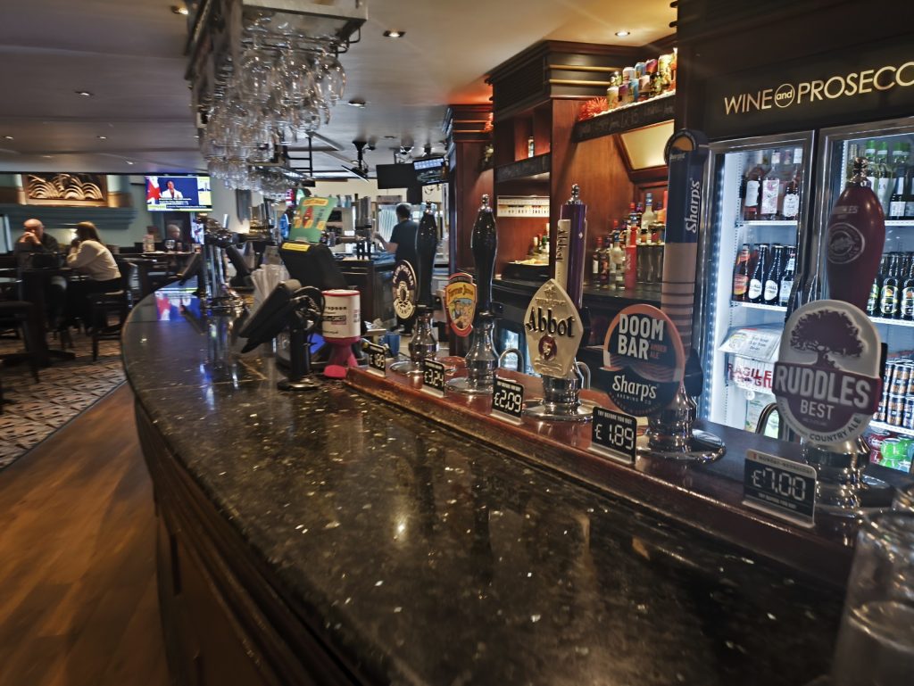 Bar at Wetherspoons Forum in Hexham showing various real ale pumps and bottled drinks