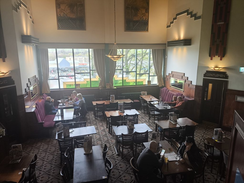 High ceilinged seating area in the former cinema that is Wetherspoons Forum in Hexham showing tables and diners