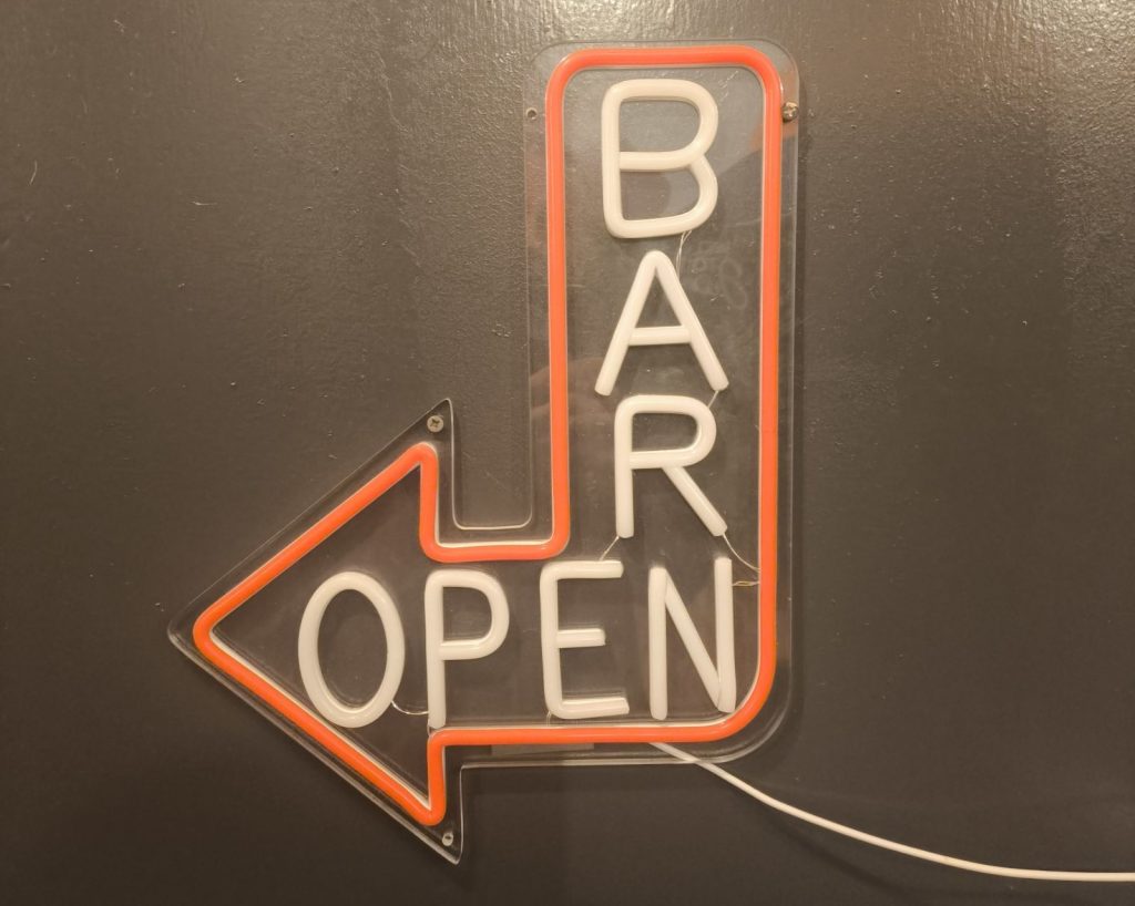 A neon "BAR OPEN" sign pointing to the left.