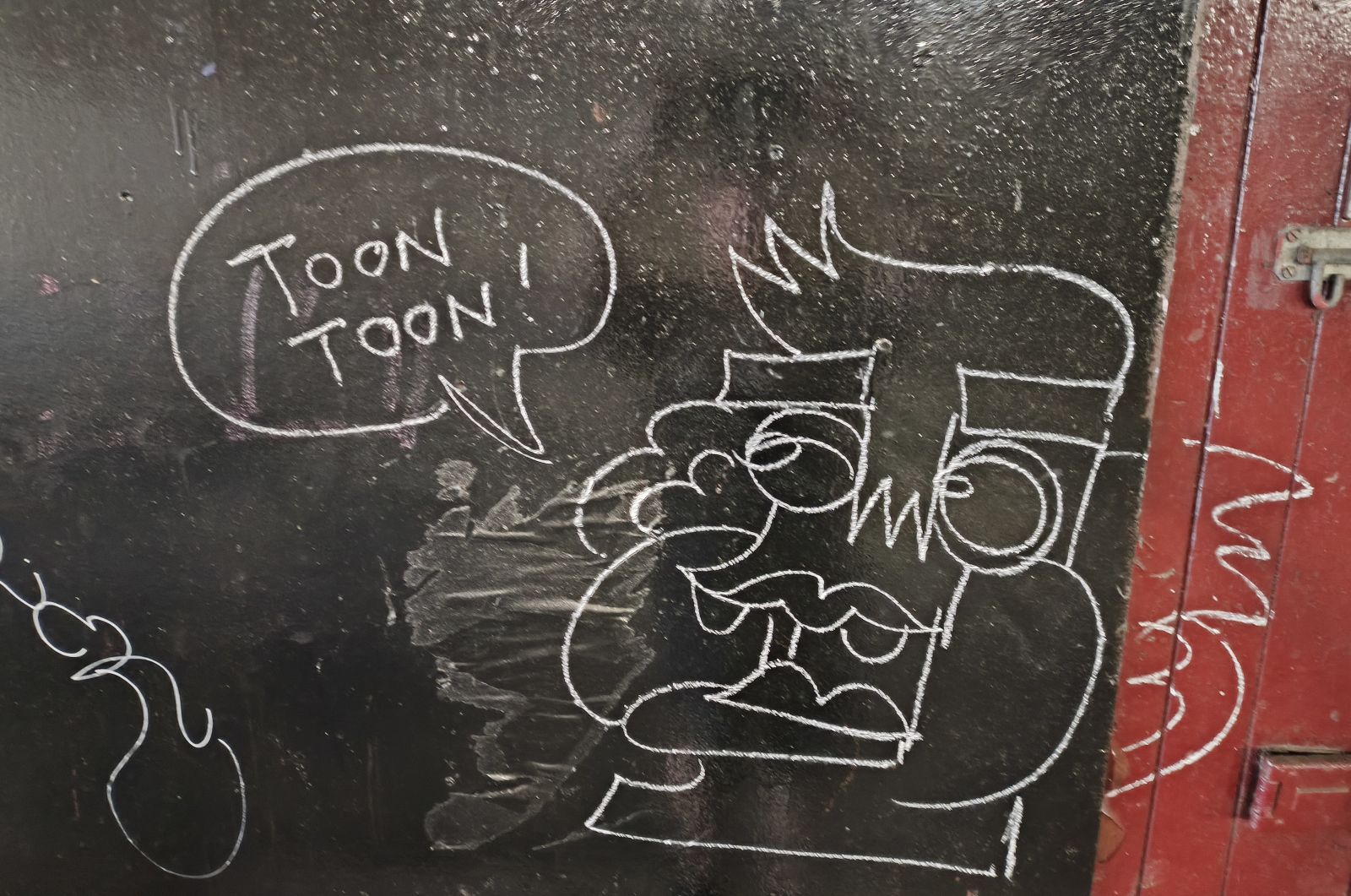 White graffiti on a black background with a cartoon character and speech bubble with "Toon Toon"