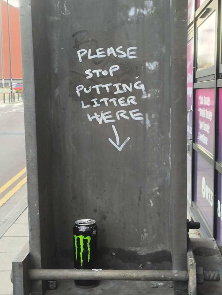 Graffiti on a post in NEwcastle "please stop putting litter here" with litter below.
